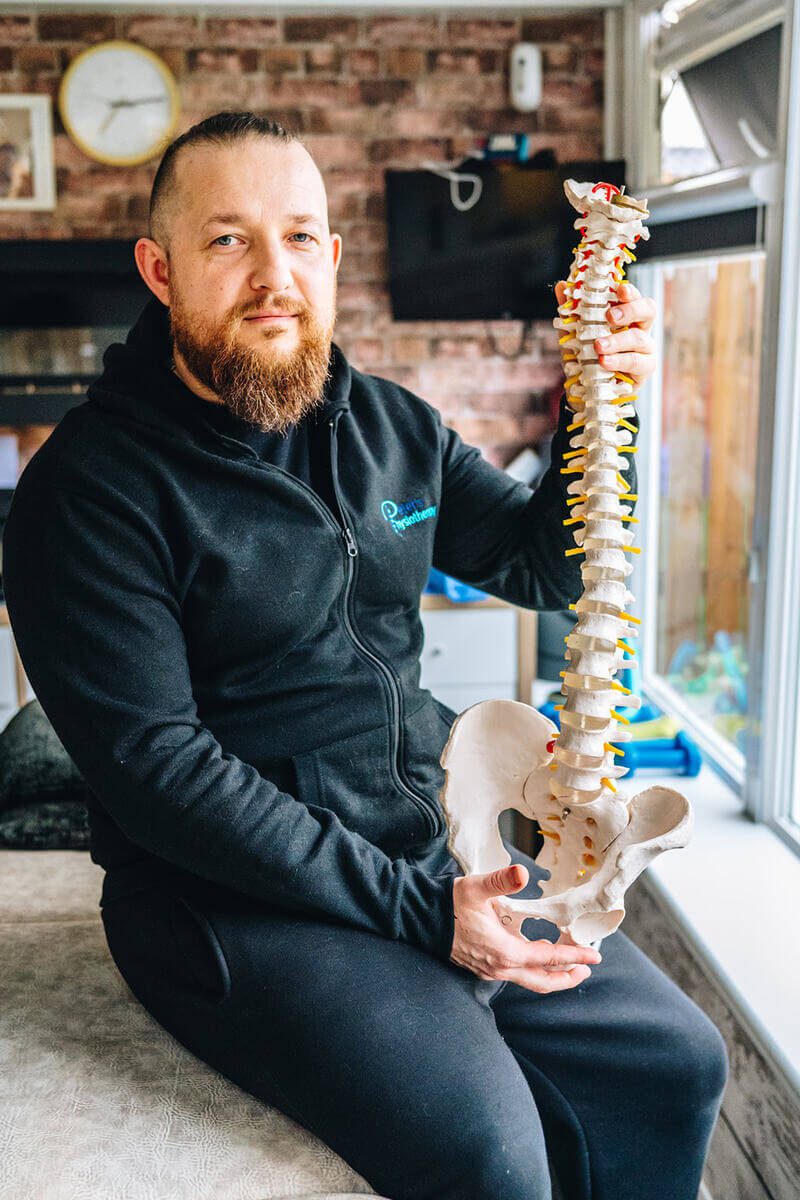 Physiotherapist in Glasgow holding a spine model for educational purposes.