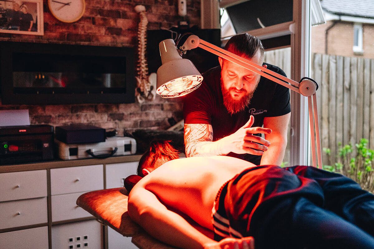 Physiotherapist using an infrared lamp for warmth and healing during therapy in Glasgow