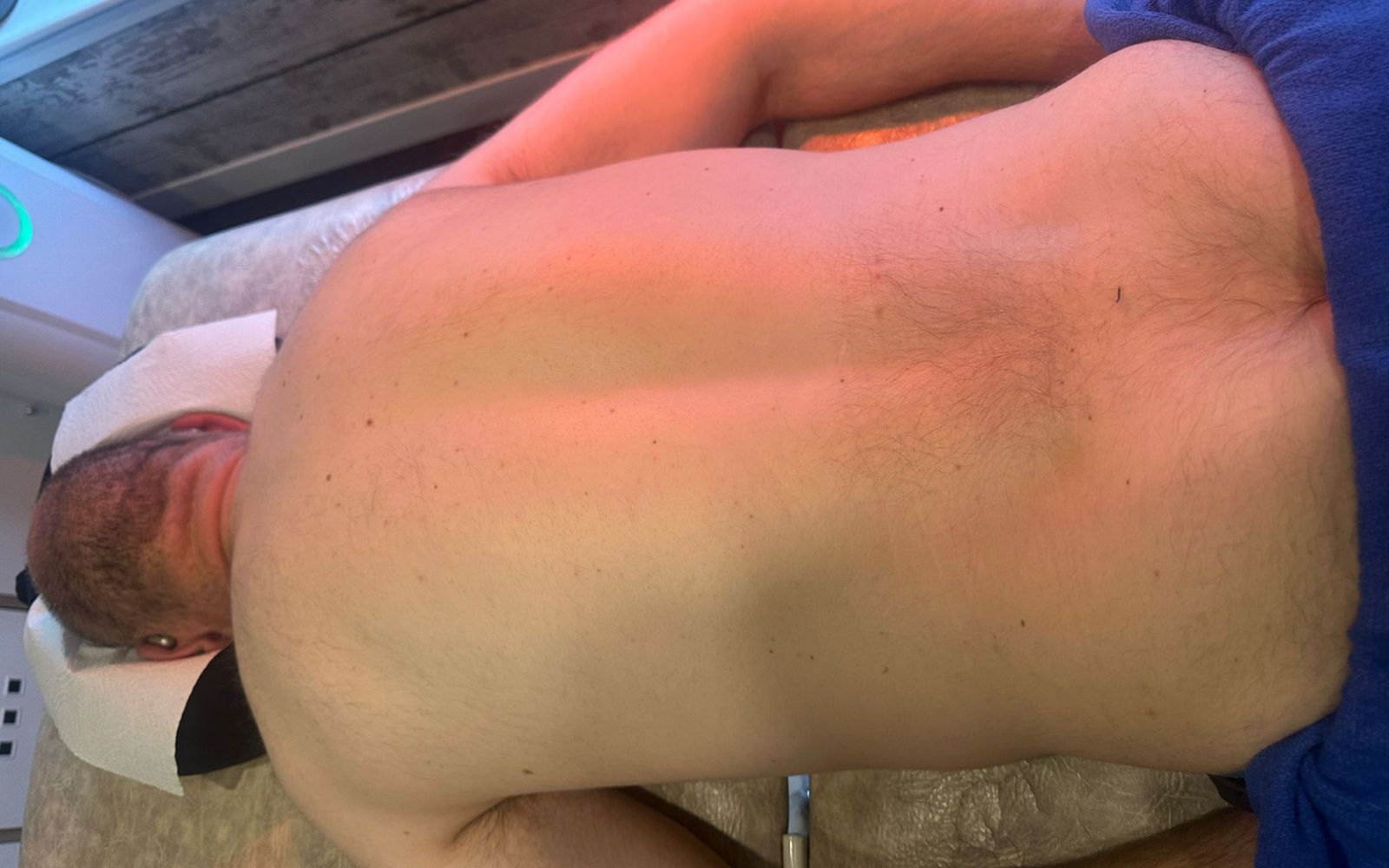 Man lying face down on a treatment table for lower back pain assessment or therapy.