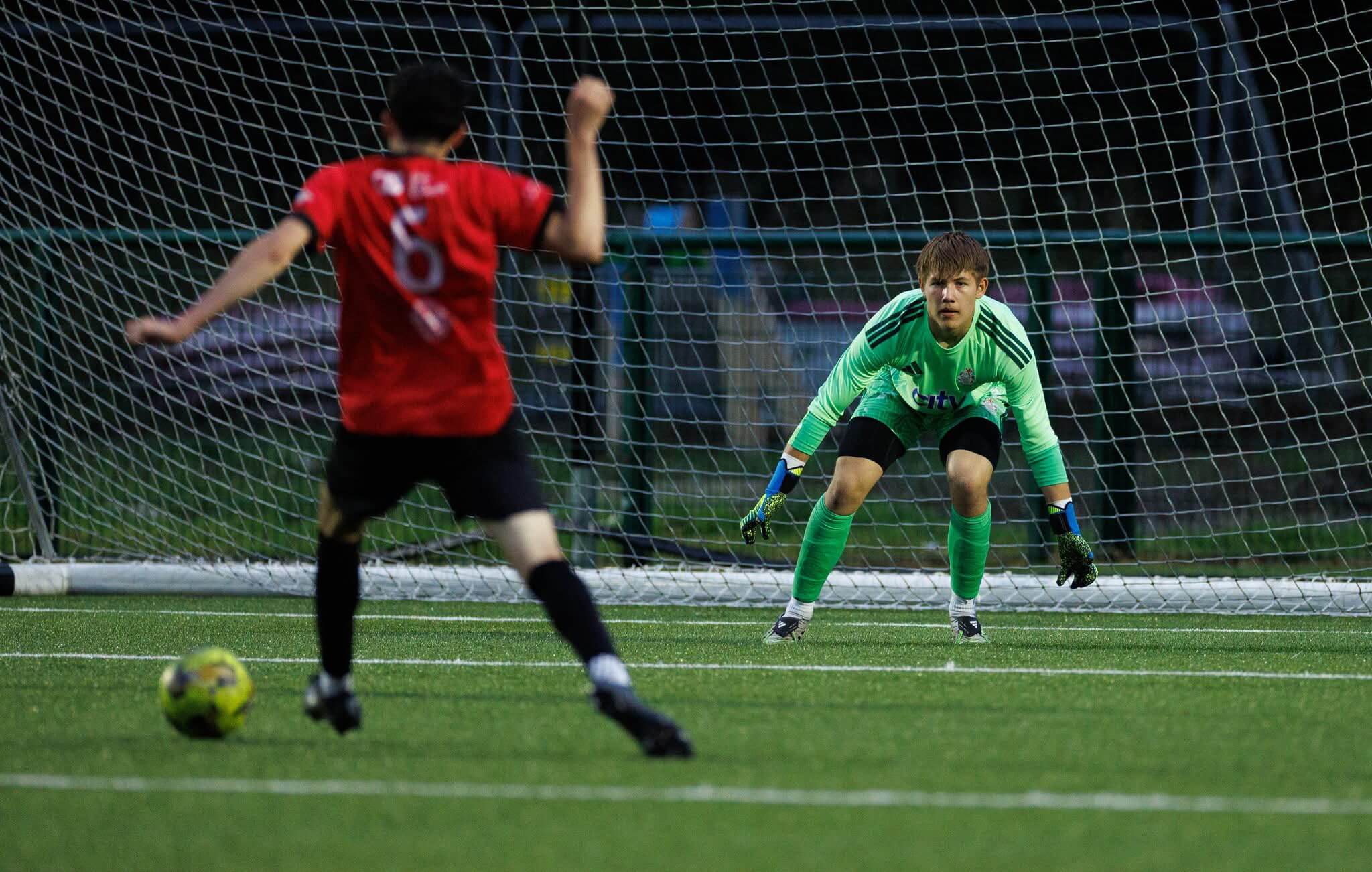 Goalkeeper in a green match kit observing the game. Effective sports physiotherapy is the foundation of a long-lasting career for active athletes.
