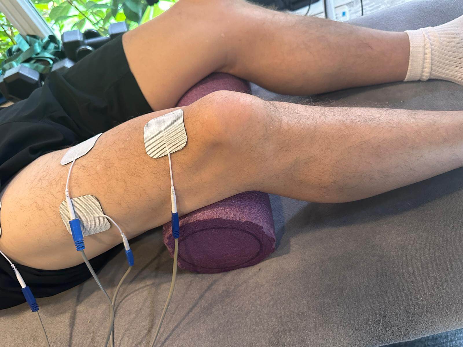 Knee physio session using electrotherapy with leg supported on foam roller in Glasgow clinic
